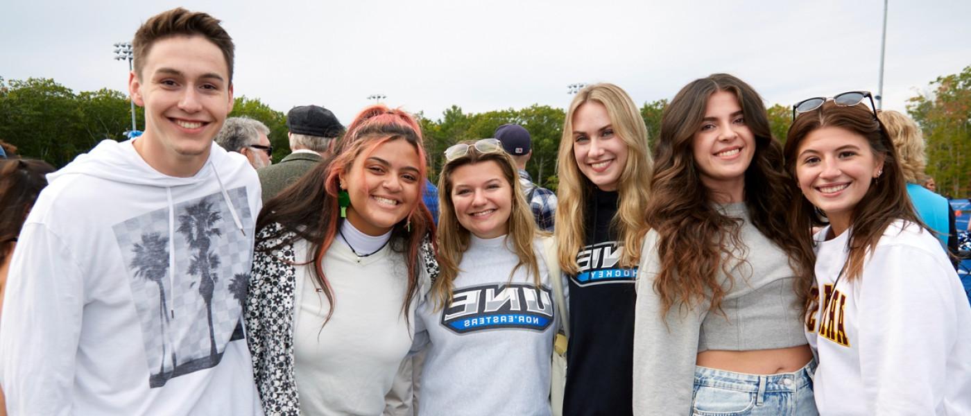 Several students standing together at a U N E 首页coming football game